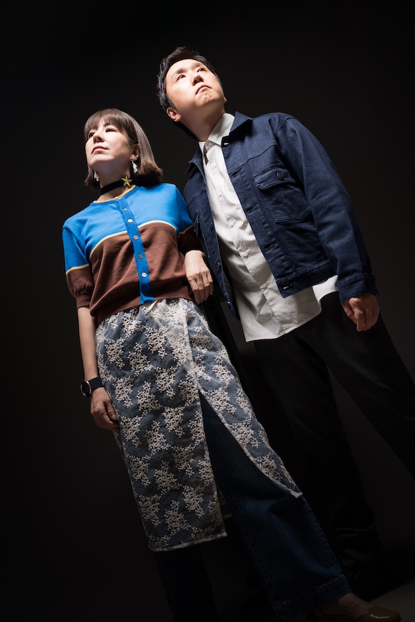 下から見上げた夫婦のクールな立ち姿 大人カップルの記念撮影 バウリニューアル カジュアルスタイル